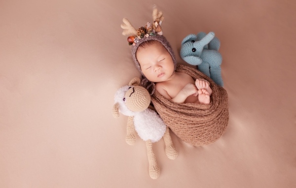 Маленький ребенок в костюме оленя с игрушкой