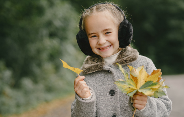 Улыбающаяся девочка с опавшими листьями в руках