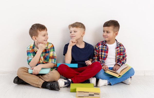 Три мальчика с книгами сидят у стены