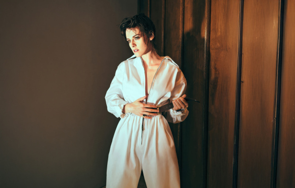 Американская актриса Кристен Стюарт в белом комбинезоне у стены