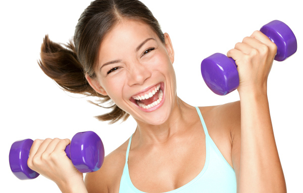 Веселая спортивная девушка с гантелями в руках
