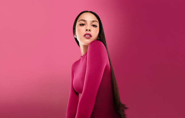 Длинноволосая актриса Оливия Родриго на розовом фоне