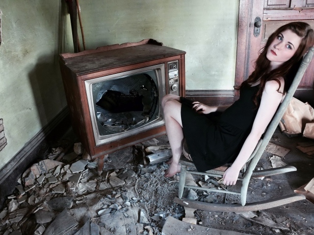 Девушка сидит у разбитого старого телевизора