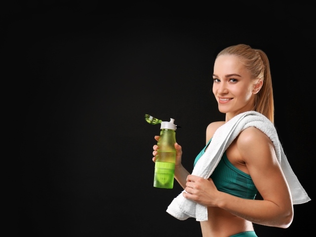 Спортивная девушка блондинка с бутылкой воды в руке