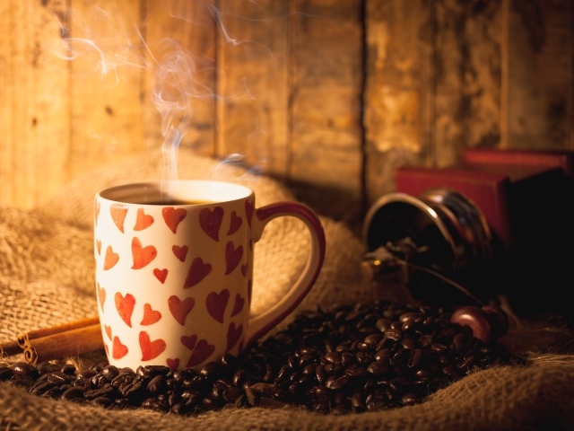 Чашка с горячим кофе на столе с кофейными зернами и корицей
