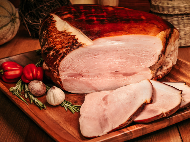 Аппетитный кусок ветчины с перцем и чесноком на доске