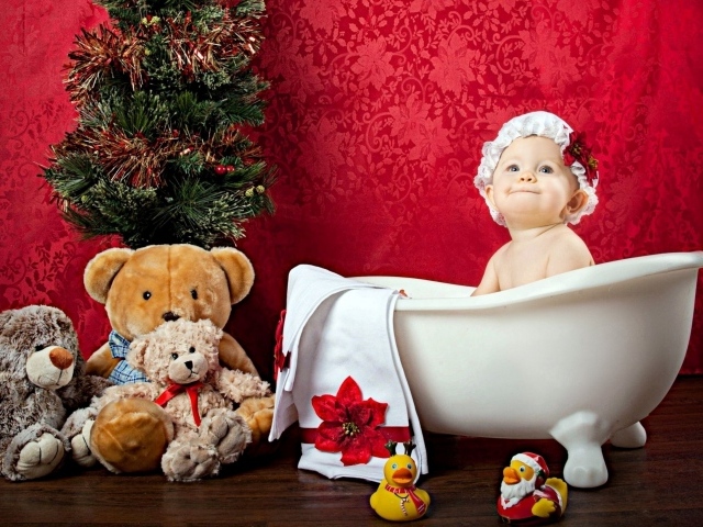 Маленькая девочка сидит в белой ванне у елки с игрушками