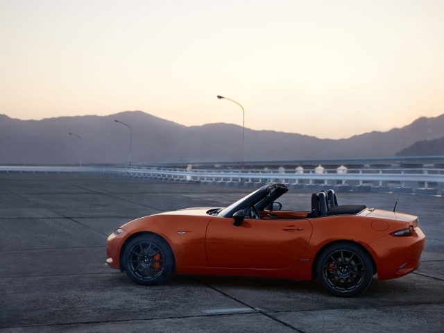 Оранжевый автомобиль кабриолет Mazda MX-5 на фоне неба