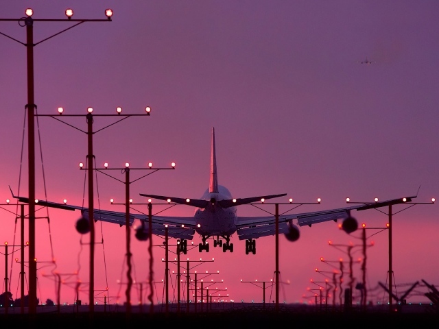 Пассажирский самолет идет на посадку на закате 