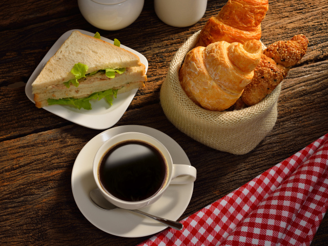 Чашка кофе с круассанами и сендвичем на завтрак