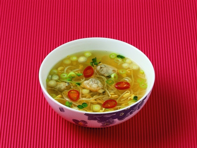 Тарелка супа с морепродуктами на красном фоне