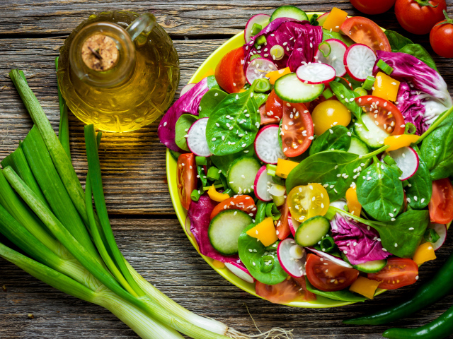 Овощной салат на столе с оливковым маслом и зеленым луком
