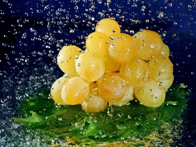 Гроздь белого винограда в брызгах воды