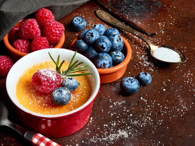 Пудинг на столе с ягодами малины и черники