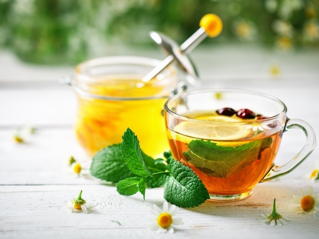 Чашка чая с лимоном и мятой на столе с медом