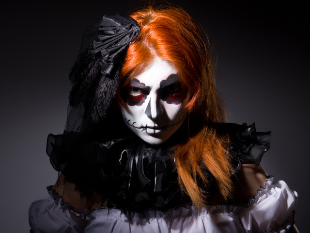 Рыжеволосая девушка с маской на лице на Хэллоуин 