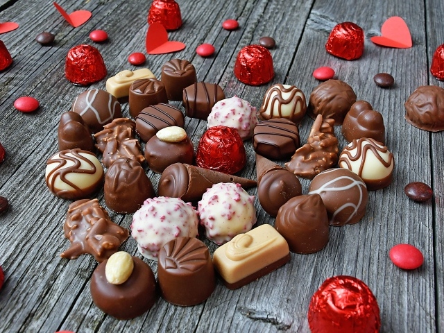 Сладкое сердце из шоколадных конфет на деревянном столе