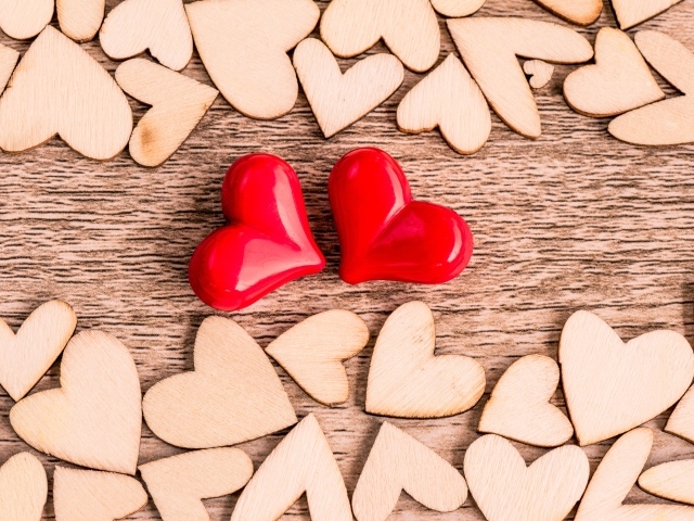 Два красных сердечка на столе с деревянными сердечками