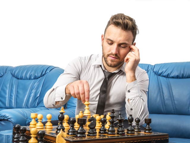 Man playing chess on a blue sofa