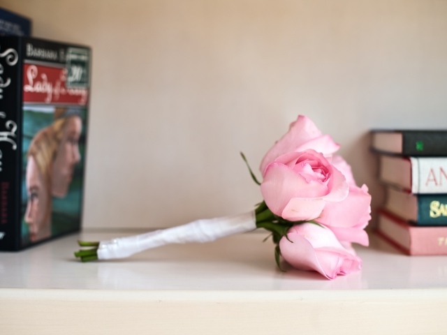 Букет розовых роз лежит на полке с книгами