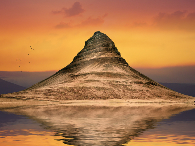 Гора отражается в воде на фоне неба на закате