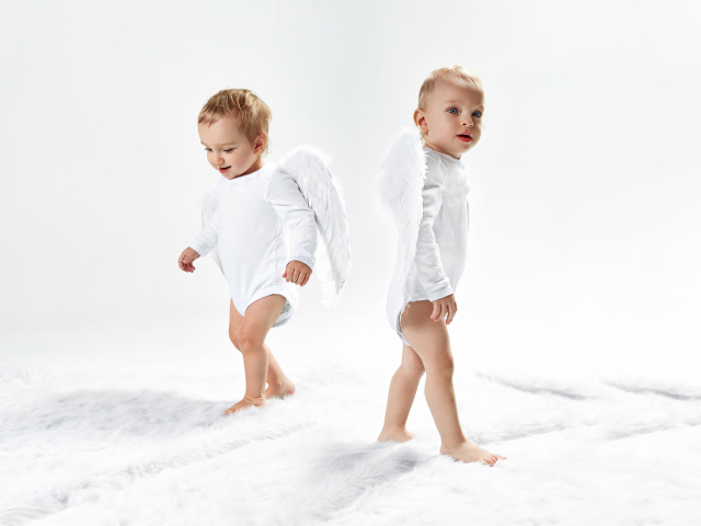 Два маленьких мальчика в костюмах ангела на белом фоне