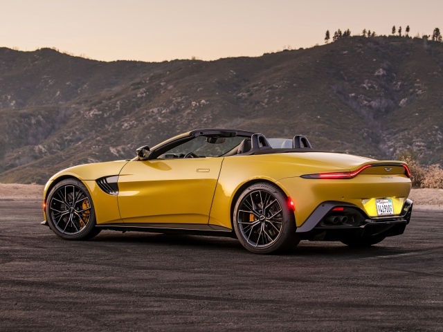Желтый автомобиль  Aston Martin Vantage Roadster, 2021 года на фоне гор 