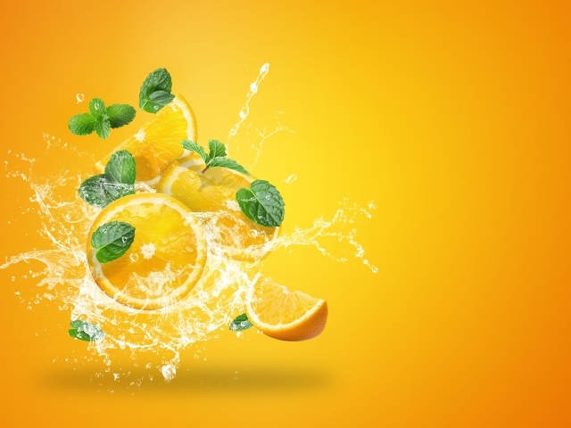 Куски апельсина в брызгах воды на оранжевом фоне