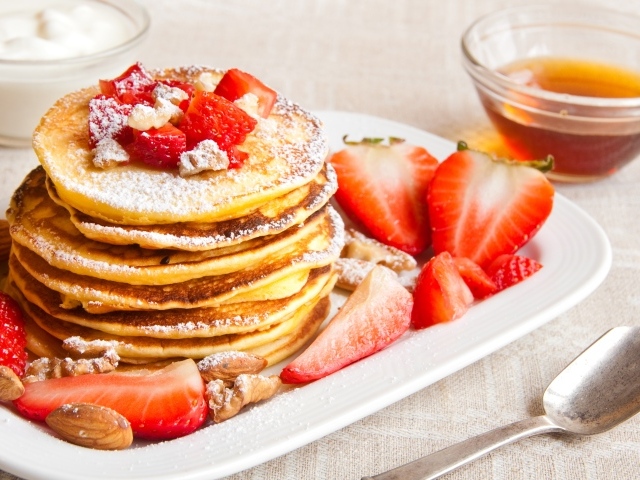 Appetizing sweet pancakes with icing sugar and strawberries