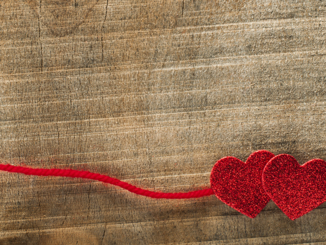Two red hearts with a lace on a wooden background