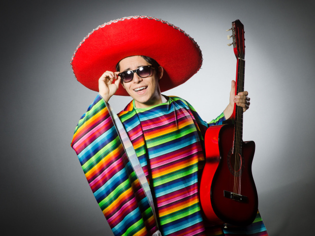 A man in a red sombrero with a guitar in his hands on a gray background