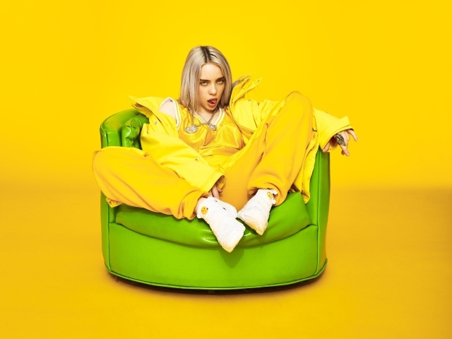 Певица Билли Айлиш сидит в кресле на желтом фоне