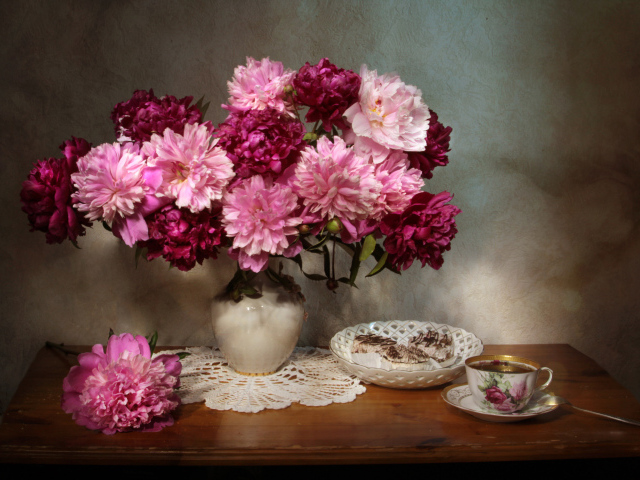 Большой букет розовых пионов в вазе на столе 