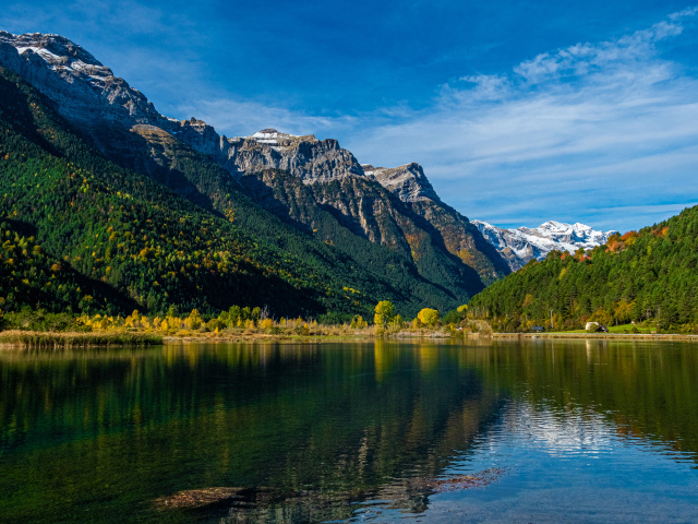 Холодная вода в чистом озере у горы под голубым небом