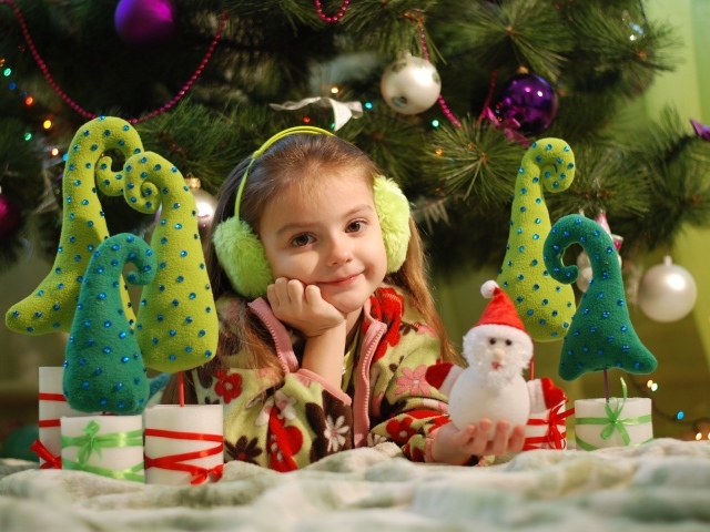 Милая маленькая девочка с игрушками под елкой 