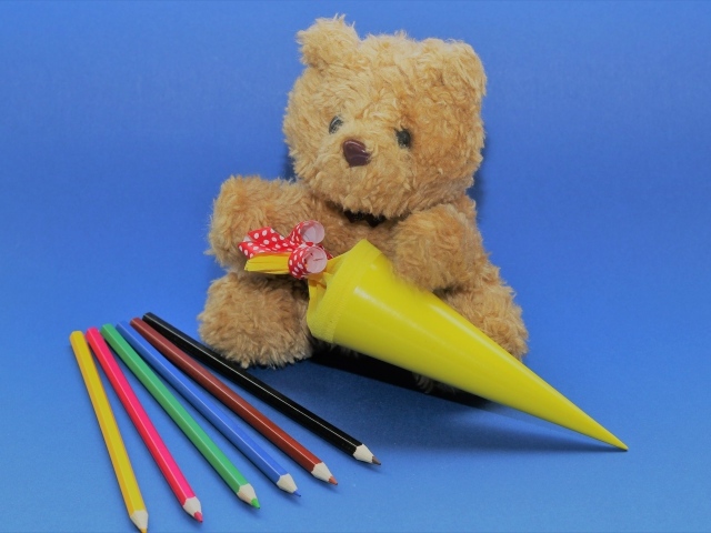 Игрушечный медвежонок  с карандашами на синем фоне