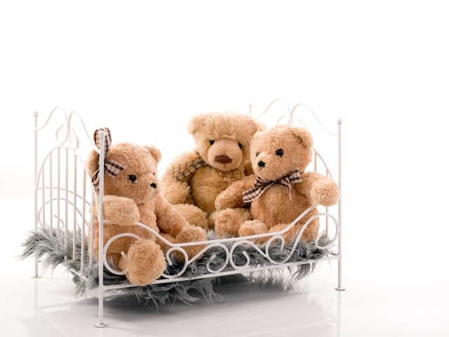 Three toy bears on the bed on a white background