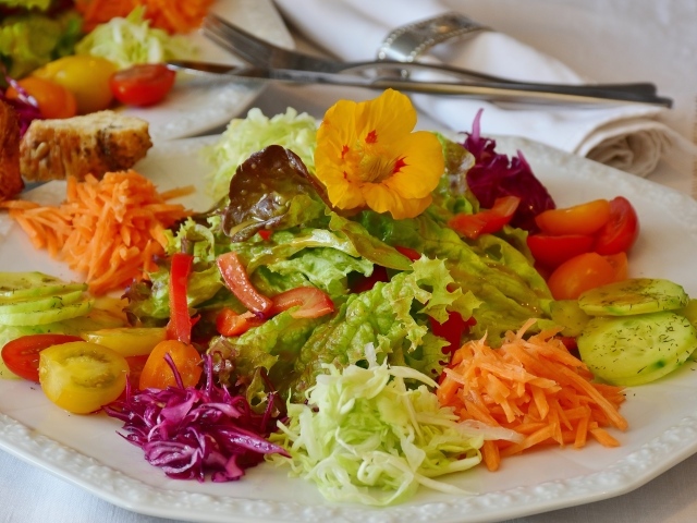 Fresh vegetables and herbs salad on a large white plate