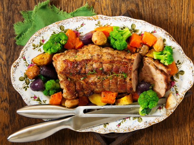 A piece of baked pork on a plate with vegetables