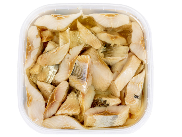 Pieces of herring in a jar with butter on a white background