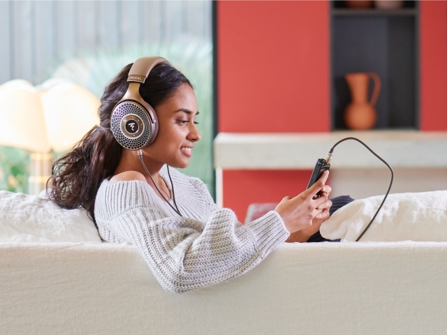 Girl model in headphones on the couch with a player
