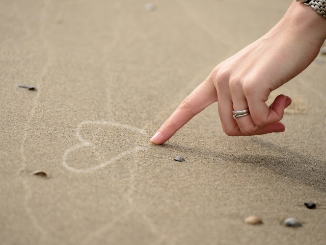 Girl draws a heart on the sand