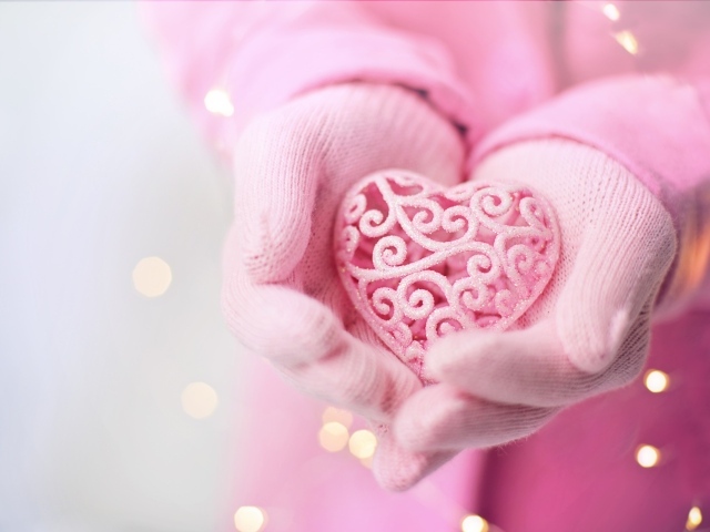 Розовое плетеное сердце в руках у девушки в перчатках 
