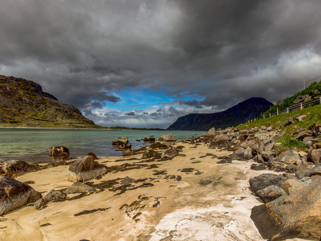 Большие камни на берегу фьорда под грозовым небом 