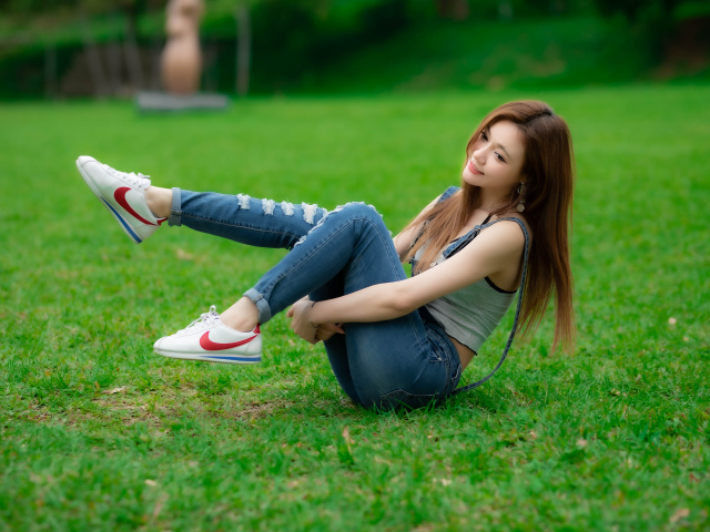 Asian girl lies in the park on the grass