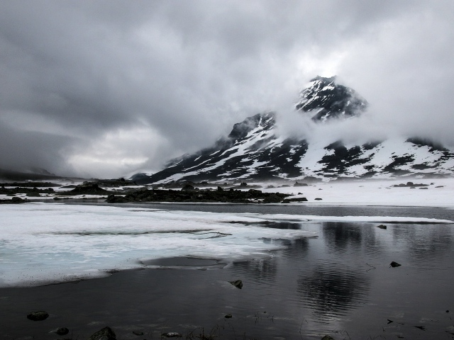 Холодный серый туман над заснеженной горой у озера