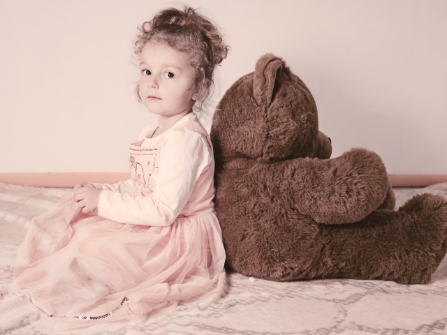 Little girl sitting with a big bear