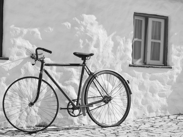 Черный велосипед стоит у белой стены