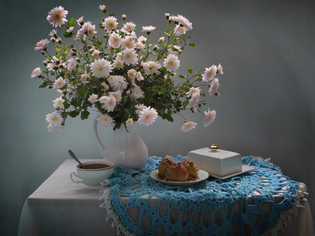Букет белых хризантем стоит на столе с чаем