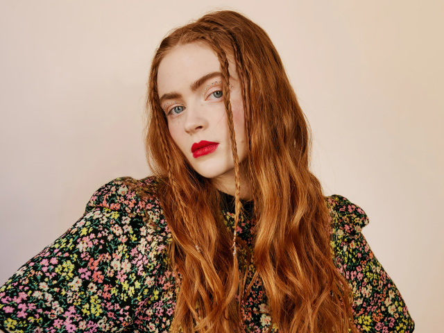 Red-haired Sadie Sink on a pink background